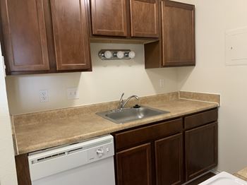 A kitchen with brown cabinets and a white dishwasher.